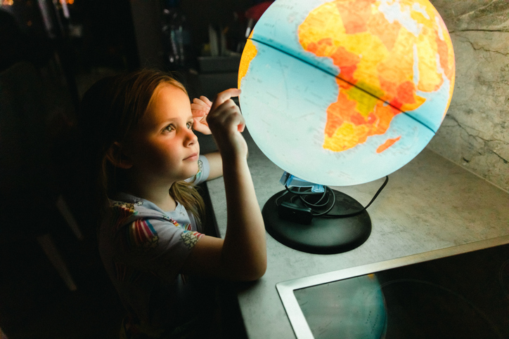Little Girl Searching Countries on a Lit Up Globe